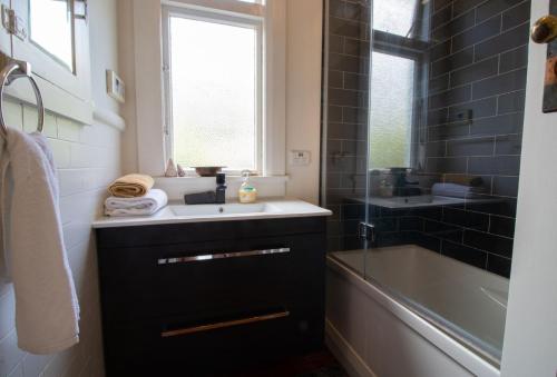 een badkamer met een wastafel, een bad en een raam bij Bungalow Eight in New Plymouth