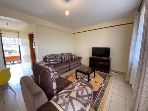 a living room with couches and a flat screen tv at Hill View Place in Nyeri