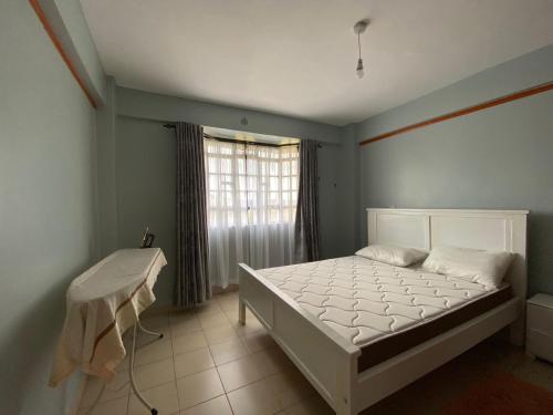 a bedroom with a white bed and a window at Hill View Place in Nyeri