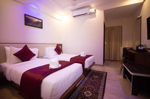 a hotel room with two beds and a television at Hotel Grand Villa in Yelahanka