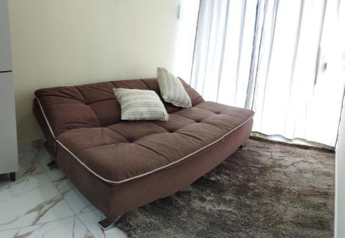 um sofá castanho com duas almofadas num quarto em Morada do bosque em Capão da Canoa