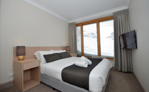 a bedroom with a bed with a teddy bear on it at Smiggins Hotel & Chalet Apartments in Perisher Valley