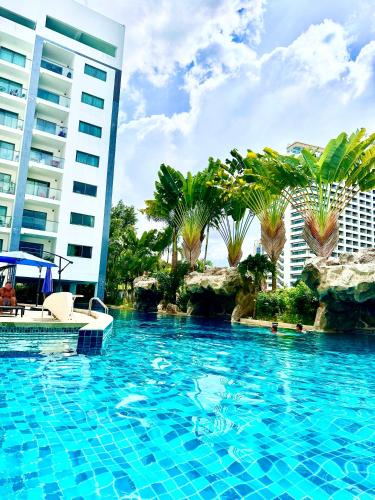 a swimming pool in front of a building with palm trees at Club Royal Apartments in North Pattaya