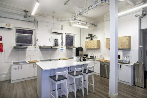 a large white kitchen with a counter and stools at Tequila Sunrise Hostel Adelaide in Adelaide