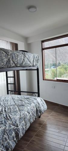 1 dormitorio con 2 literas y ventana en Casa Arin valle sagrado de los inkas, en Cusco