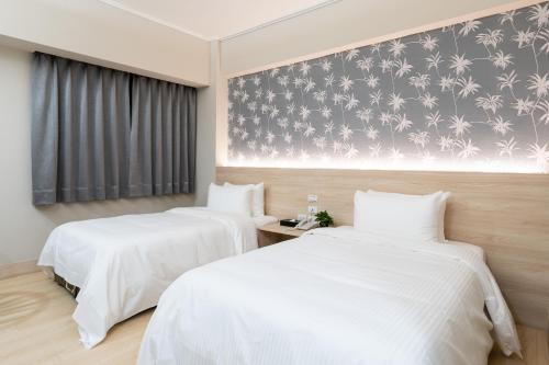 duas camas num quarto de hotel com lençóis brancos em Etung Hotel em Taichung