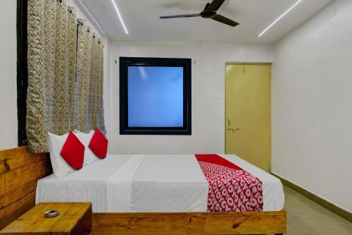 a bedroom with a bed with red pillows and a window at OYO Hotel Paradise in Pune