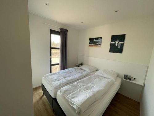 a bedroom with two beds and a window at Marina Strandbad Chalet Aan het Strand mit Zaun Haus Nr 133 in Olburgen