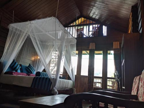a bedroom with a canopy bed in a room with windows at Madushanka Resort in Ella