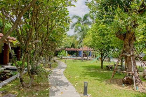 a path through a park with trees and a building at Namsai Resort Kanchanaburi in Kanchanaburi