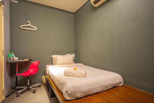 a bedroom with a bed and a red chair at Ryokan Chic Hotel in Petaling Jaya
