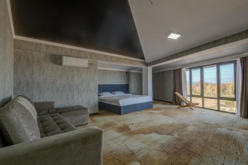 a bedroom with a bed and a couch in a room at Vzmorie Resort Hotel in Bosteri