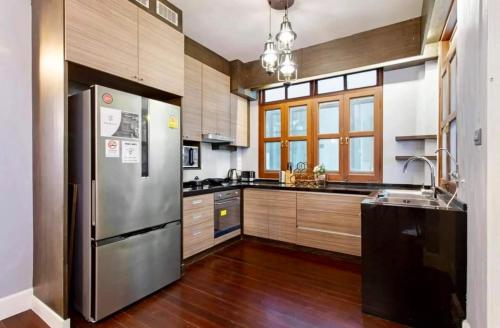 a kitchen with a stainless steel refrigerator and wooden cabinets at Sathorn Private Pool Villa in Bangkok
