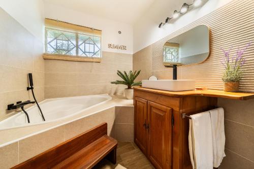 a bathroom with a tub and a sink and a mirror at Villa à la Plage, lagon à 500m, climatisée in Saint-Paul