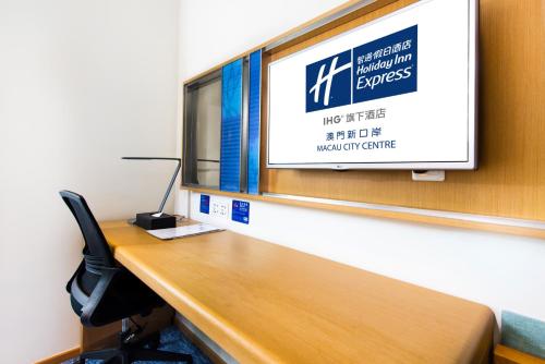 an office cubicle with a desk and a tv on a wall at Holiday Inn Express Macau City Centre by IHG in Macau