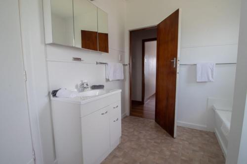 uma casa de banho branca com um lavatório e um espelho em Spacious In Strandon Great Value For A Family em New Plymouth