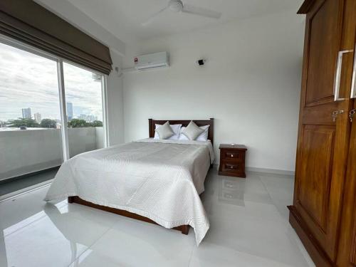 a white bedroom with a bed and a large window at Luxury 3 bed flat in Colombo 7 in Colombo