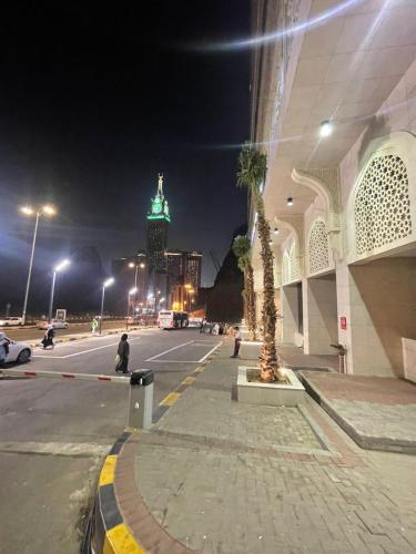 a city street at night with a building with a palm tree at Nawazi Towers Hotel in Makkah
