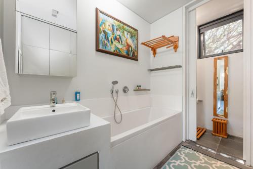 a white bathroom with a sink and a bath tub at 10 Dash Apartment, Dunkirk in Sheffield Beach