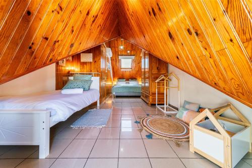 a attic bedroom with a bed and wooden ceilings at Villa à la Plage, lagon à 500m, climatisée in Saint-Paul