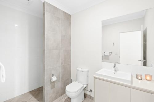 a white bathroom with a toilet and a sink at Blue Lagoon Villa B in Cairns