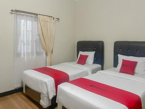 two beds sitting next to each other in a room at RedDoorz Syariah at Bumi Eyang Enin Homestay Tasikmalaya in Tasikmalaya