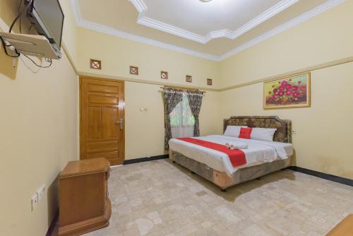 um quarto com uma cama e uma televisão num quarto em RedDoorz Syariah at Bumi Eyang Enin Homestay Tasikmalaya em Tasikmalaya