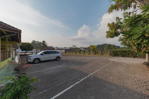 a white car parked in a parking lot at RedDoorz Syariah at Bumi Eyang Enin Homestay Tasikmalaya in Tasikmalaya
