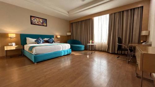 een hotelkamer met een bed en een groot raam bij The Conway in Meerut