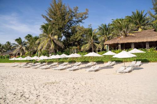 a row of white chairs and umbrellas on a beach at Pax Ana Doc Let Resort & Spa in Ninh Hòa