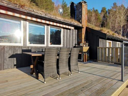 una terraza de madera con mesa y sillas. en 4 person holiday home in ydegard, en Torvikbukt