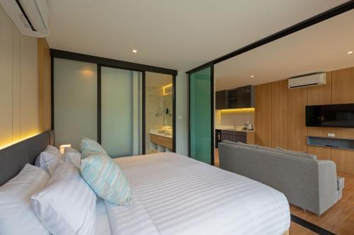 a bedroom with a large white bed and a kitchen at Wyndham Garden Naithon Phuket in Nai Thon Beach