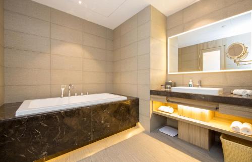 a bathroom with a tub and a sink and a mirror at Atour Hotel Chongqing Hongyadong Riverview in Chongqing