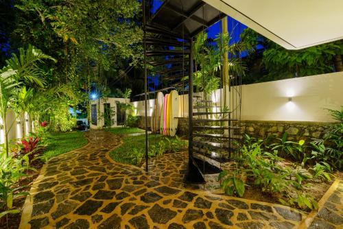 a walkway in a garden with surfboards on a wall at Terra Resort in Ahangama