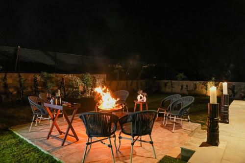a group of chairs around a fire pit at night at SaffronStays Villa Rohi in Udaipur