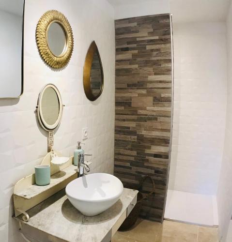 une salle de bain avec un lavabo et deux miroirs dans l'établissement Appartements Cabiscol, à Beaucaire
