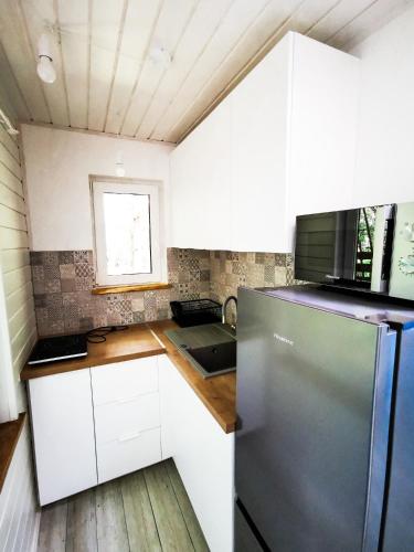 a kitchen with white cabinets and a stainless steel refrigerator at Ostoja Stacze in Stacze