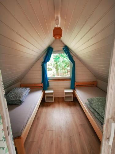 two beds in a tiny house with a window at Ostoja Stacze in Stacze