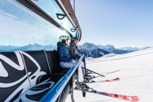 two people sitting on a ski lift in the snow at Pension Panorama in San Lorenzo di Sebato