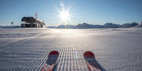 a pair of skis standing in the snow with the sun at Pension Panorama in San Lorenzo di Sebato