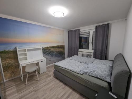 een slaapkamer met een bed en een bureau met uitzicht op het strand bij NB Vogelviertel zwei Zimmer Wohnung in Neubrandenburg