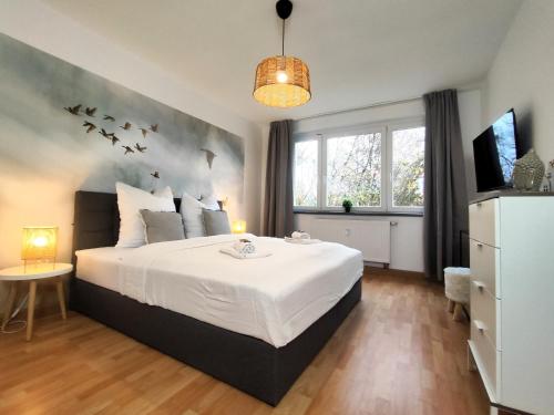 1 dormitorio con 1 cama con pájaros en la pared en BohnApartments Juwel am See, mitten in der Natur - gratis Parkplatz - Kamin - WLAN - Nähe Erfurt, en Kranichfeld