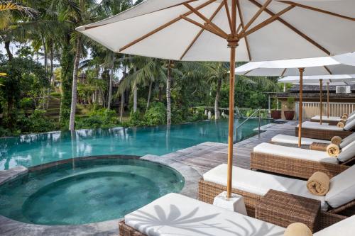 una piscina con sillas, una sombrilla y una piscina en Wapa di Ume Ubud en Ubud