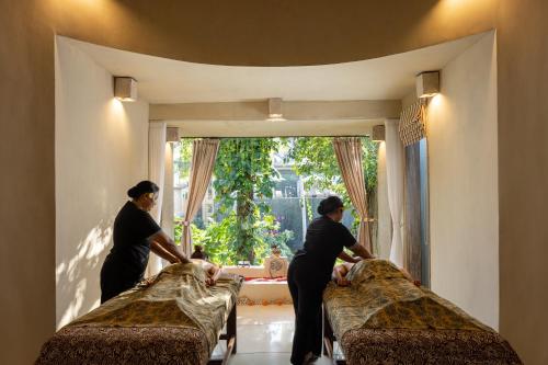 ウブドにあるWapa di Ume Ubudの窓付きの部屋 ベッドメイキング(女性3名)