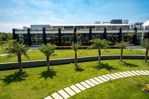 a group of palm trees in front of a building at Sportico Resort Bangalore in Mālūr