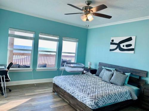 a bedroom with blue walls and a bed with a ceiling fan at OceanFront home near HollyBeach in Cameron