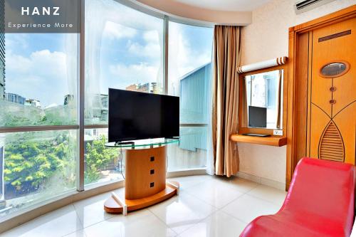 a room with a tv and a red chair in front of a window at HANZ Happy Hotel in Ho Chi Minh City