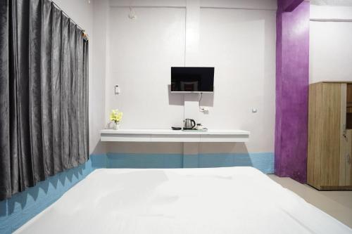 a bedroom with a bed and a tv at FA Homestay Syariah at Babat Lamongan Mitra RedDoorz in Lamongan