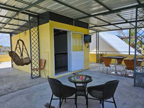 a patio with chairs and a table and a yellow building at Ushpav Villa in Cap Malheureux