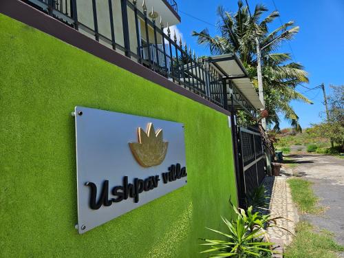 a sign on the side of a green building at Ushpav Villa in Cap Malheureux